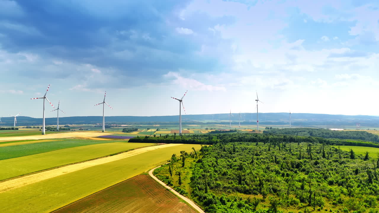 Turbines in green fields. Wind turbines stand tall in the landscape, harnessing wind energy among lush green fields and distant hills