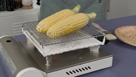 a-Japanese-female-chef-puts-shoyu-on-grilled-corn-at-her-home-kitchen,-Tokyo,-Japan