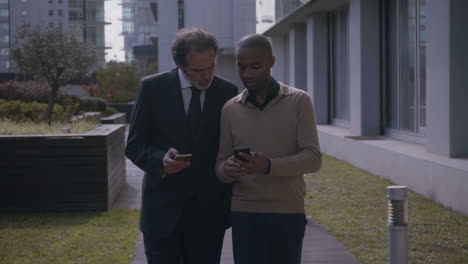 Serious-businessmen-walking-and-talking-about-smartphones-in-city