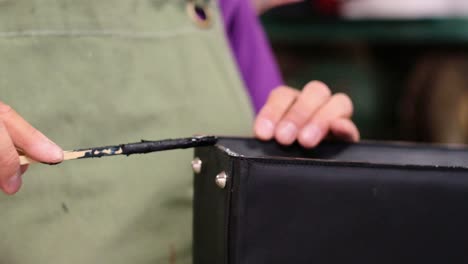 craftsman repairing a black leather bag