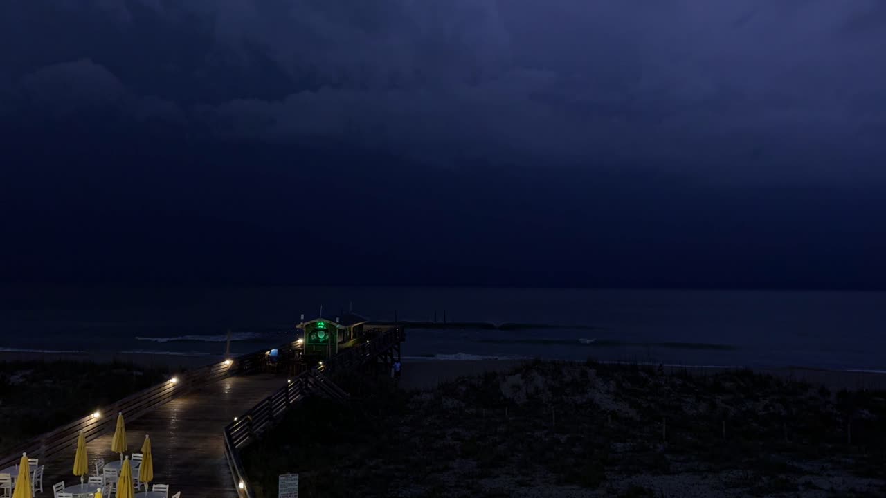 Tuoni e fulmini durante una tempesta primaverile sulla spiaggia con un molo in primo piano
