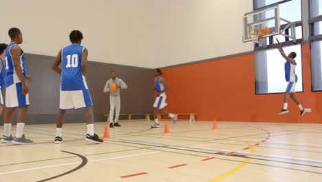 playing basketball, coach guiding players during practice session in indoor gym