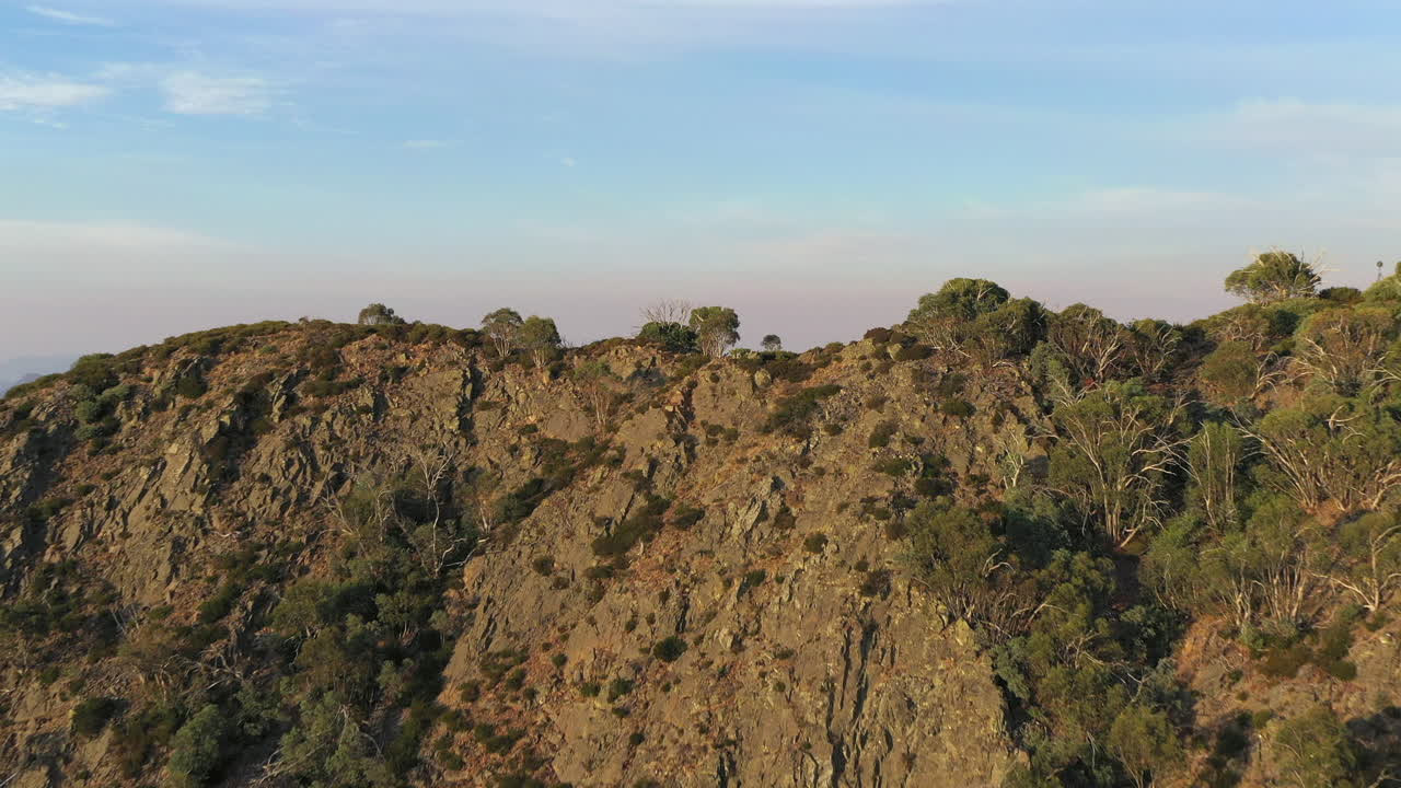 Aerial of Mountain range, treetops, in Outback Australia flyover with drone closer