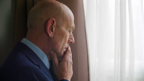 close up shot of a pensive thoughtful mature man looks out of a window