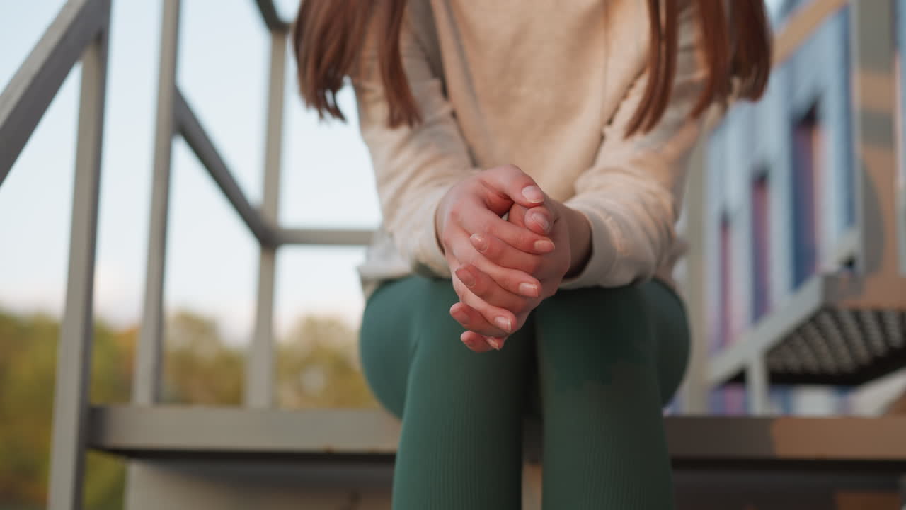 여자는 계단에서 걱정하면서 손가락을 움직이고, 젊은 여자는 긴장과 우울증의 혼합을 경험하고, 미래의 불확실성에 대해 고민하고, 불확실성의 느낌을 느니다.