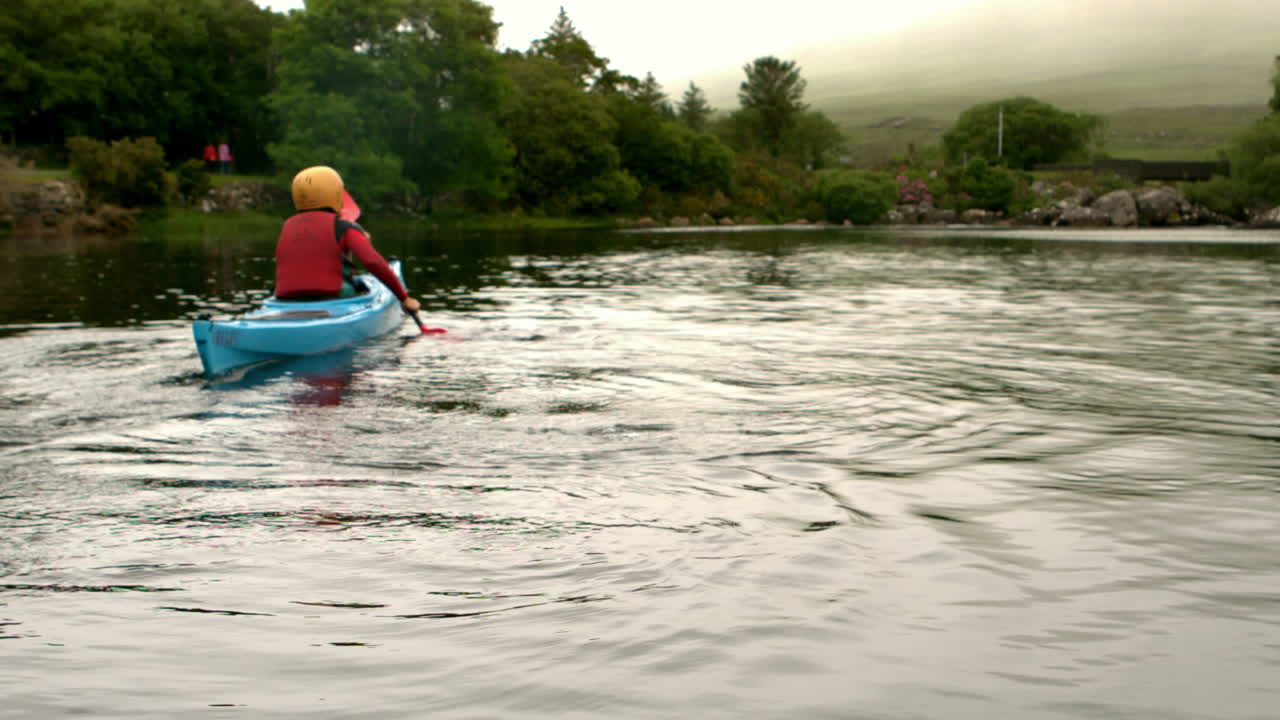 mujer en kayak en un lago en el campo