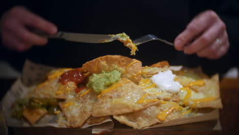 comiendo nachos mexicanos con cuchillo y tenedor con guacamole con queso y crema agria