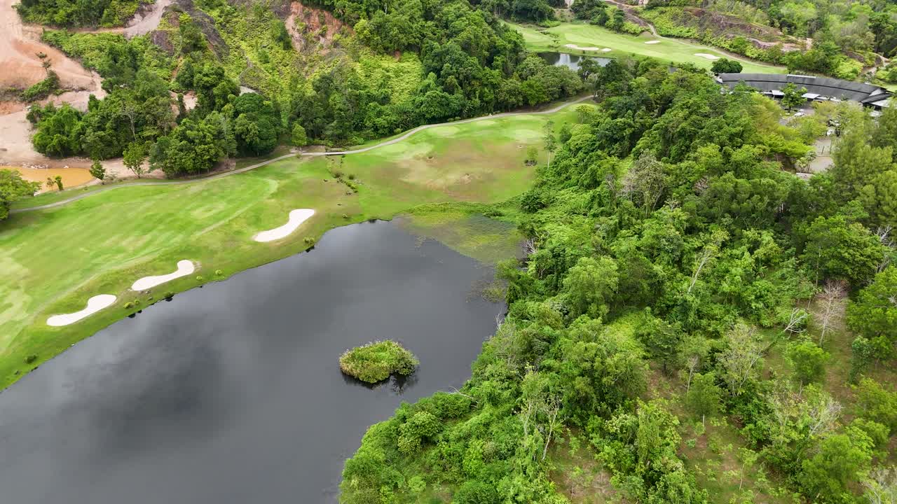 Aerial drone footage captures the lush greenery and serene water features of a luxury golf course in Phuket, Thailand