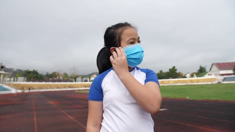 little girl takes off the medical flu mask at stadium