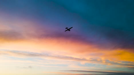 a plane flying under clouds at sunset