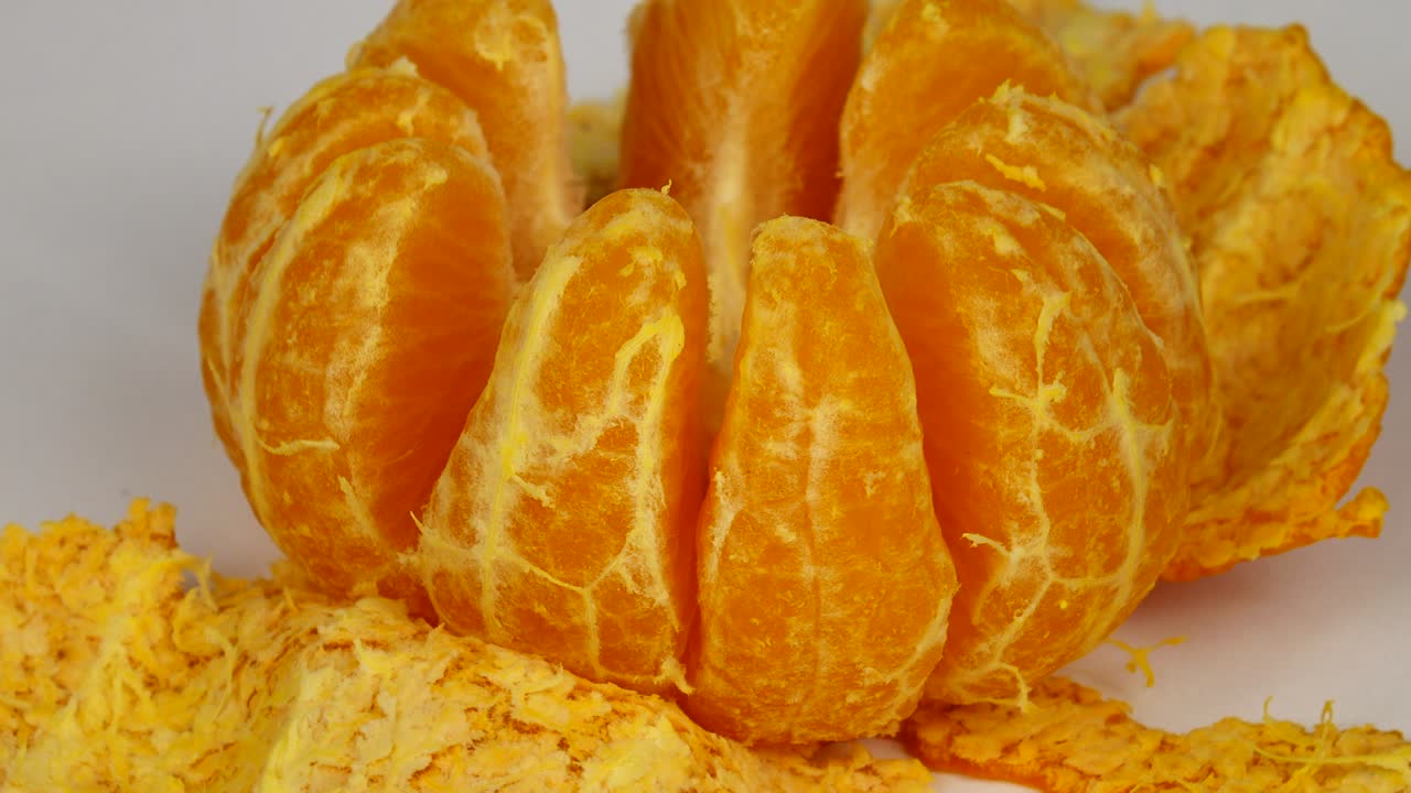 Peeled tangerine lies on a white table