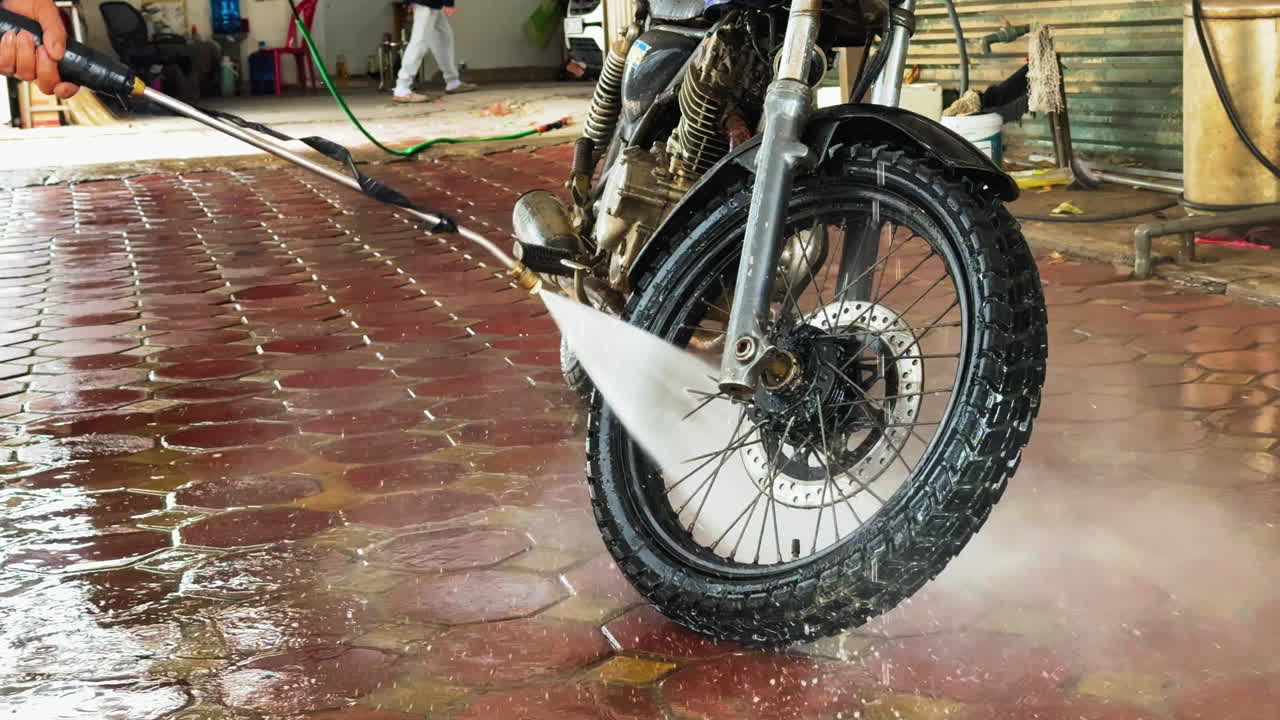 Man washing a motorcyle with a power pressure machine in a car wash in Vietnam