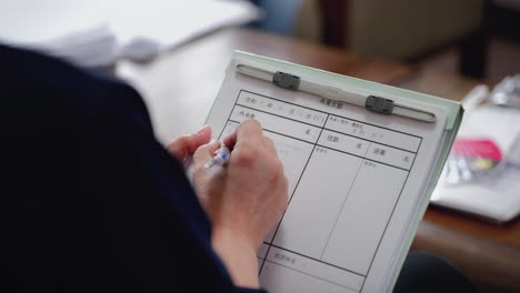 close-up of a japanese woman writing notes during a meeting