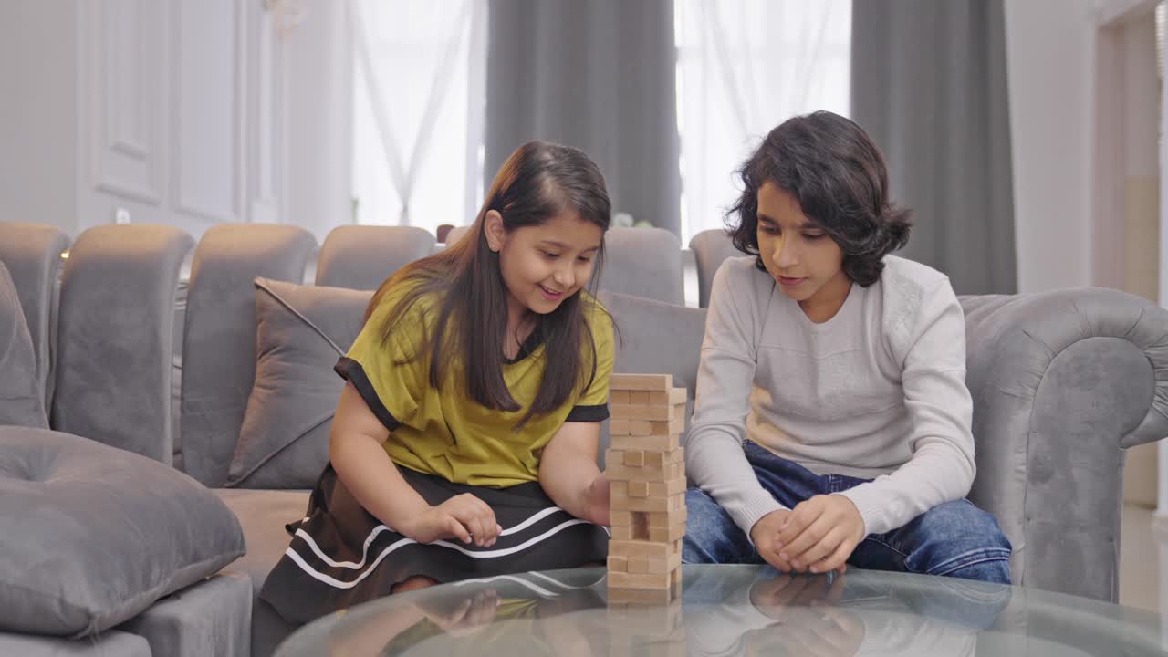 niños indios serios jugando a jenga en casa
