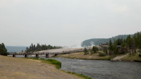 Touristen,-Die-Auf-Der-Fußgängerbrücke-Spazieren,-Während-Im-Hintergrund-Dampf-Aus-Der-Großen-Prismatischen-Quelle-Im-Yellowstone-Nationalpark,-Wyoming,-USA,-Aufsteigt