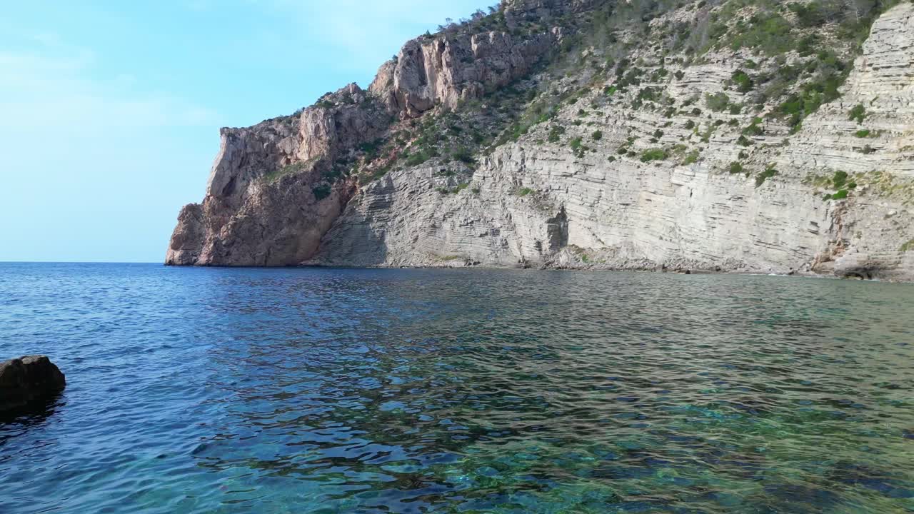 Acqua turchese trasparente scorre tra le rocce in una baia a Ibiza, Spagna. Incredibile vista aerea panoramica ripresa da drone