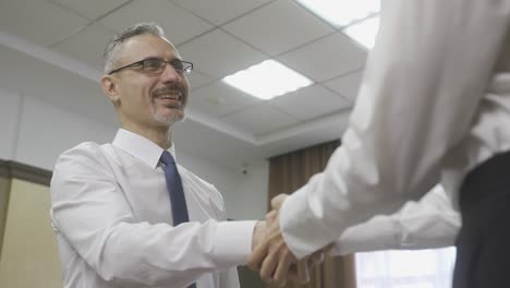 feliz empleado caucásico estrechando la mano de su jefe en la oficina