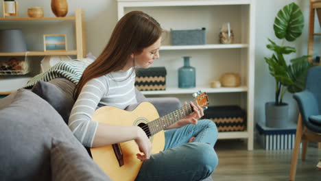 mujer tocando la guitarra en casa