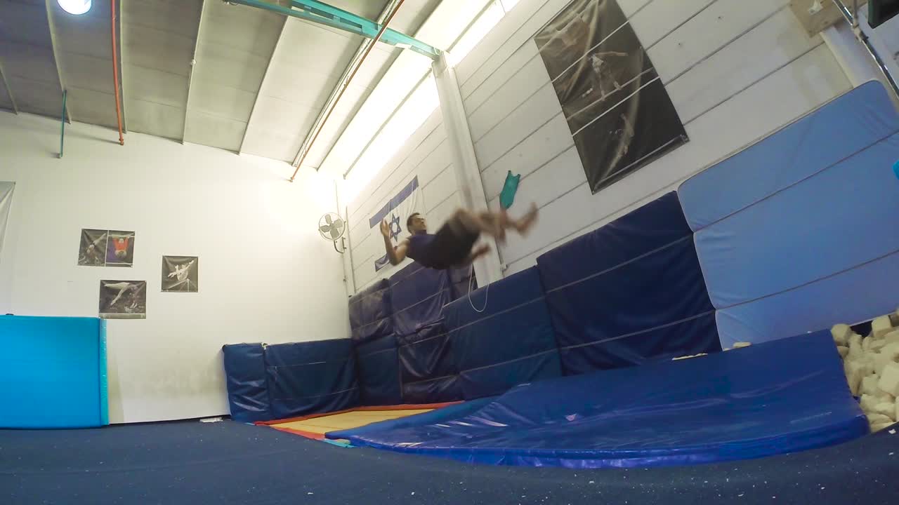 a slow motion still shot of a guy doing flips from the trampoline landing and winning having fun and working out in 60fps