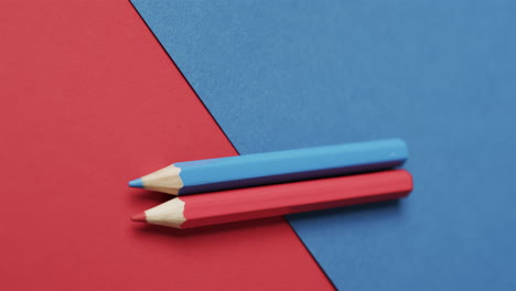 primer plano de lápices de colores azules y rojos sobre fondo rojo y azul, en cámara lenta