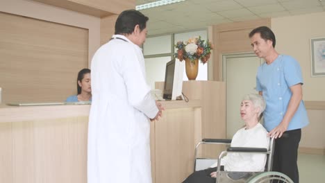 male nurse help support an elderly woman sit in a wheelchair for receiving treatment or health check with specialist doctor or personal doctor. health care, hospital, medical, insurance, retired.