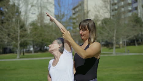 una joven sonriente entrenando con una anciana en el parque.