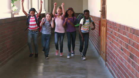 Cute-pupils-running-and-smiling-at-camera-in-hallway