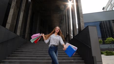 chica con bolsas de compras, girando, bailando, pareciendo satisfecha con la compra, disfrutando de descuentos de precios
