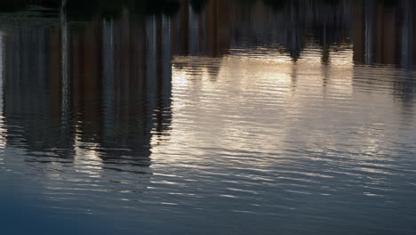 agua reflejando edificios del paisaje urbano disparado por un avión no tripulado. calma superficie del río ondulado que fluye