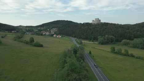 cars driving along the winding road below rabi castle rising majestically on a hill above the landscape
