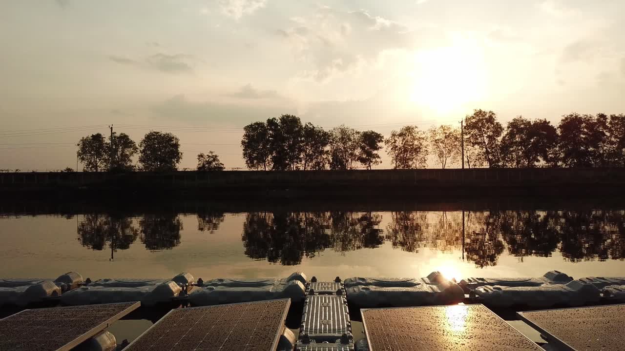 proyecto de granja solar flotante en el lago, reflejo del sol al atardecer, revelación de retroceso aéreo