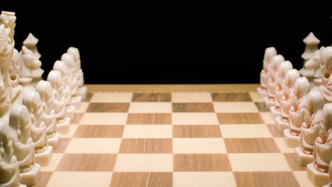 Tracking-zoom-in-through-chessboard,-Hand-playing-on-pawn