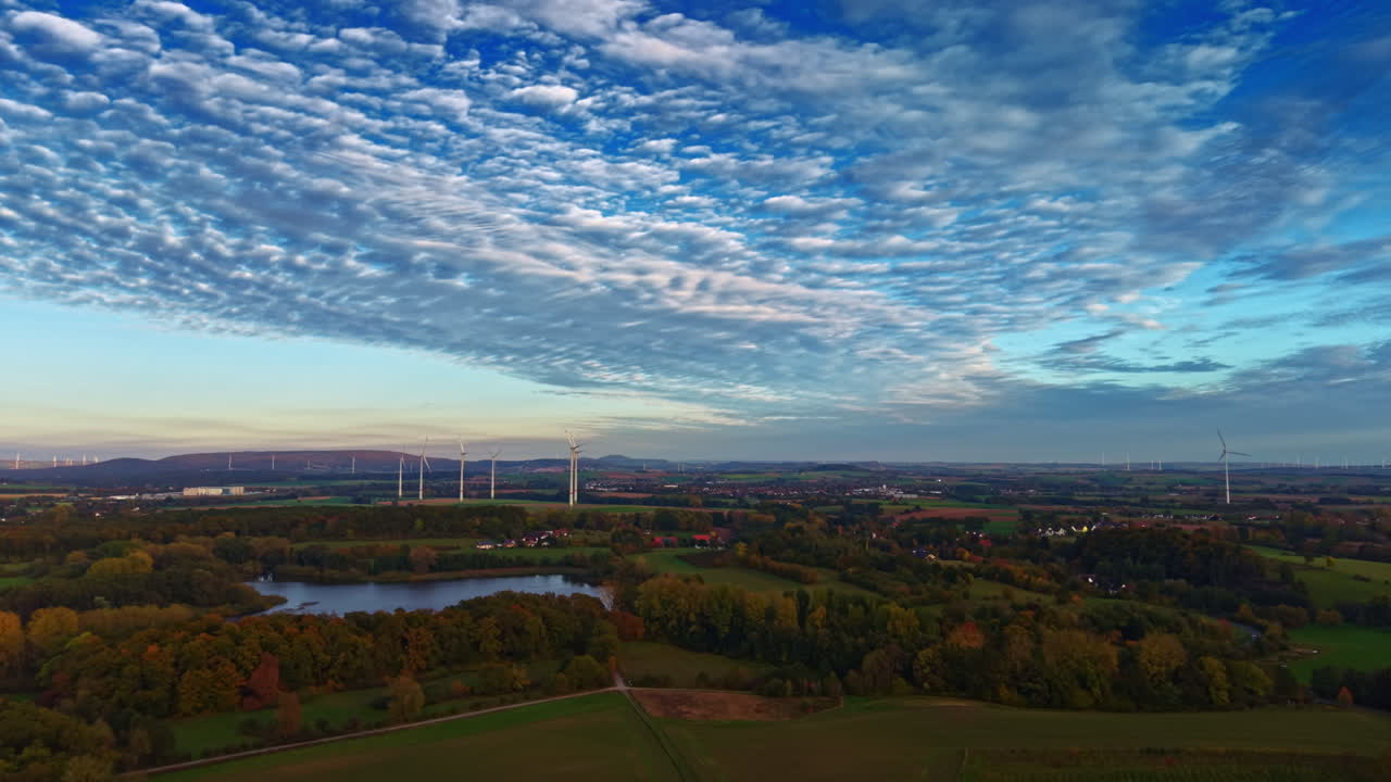 Vasto paesaggio autunnale con dolci colline e turbine eoliche che catturano l'essenza della natura e dell'energia sostenibile sotto un cielo vivido