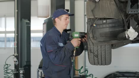 mecánico cambiando la rueda del coche con llave inglesa de impacto