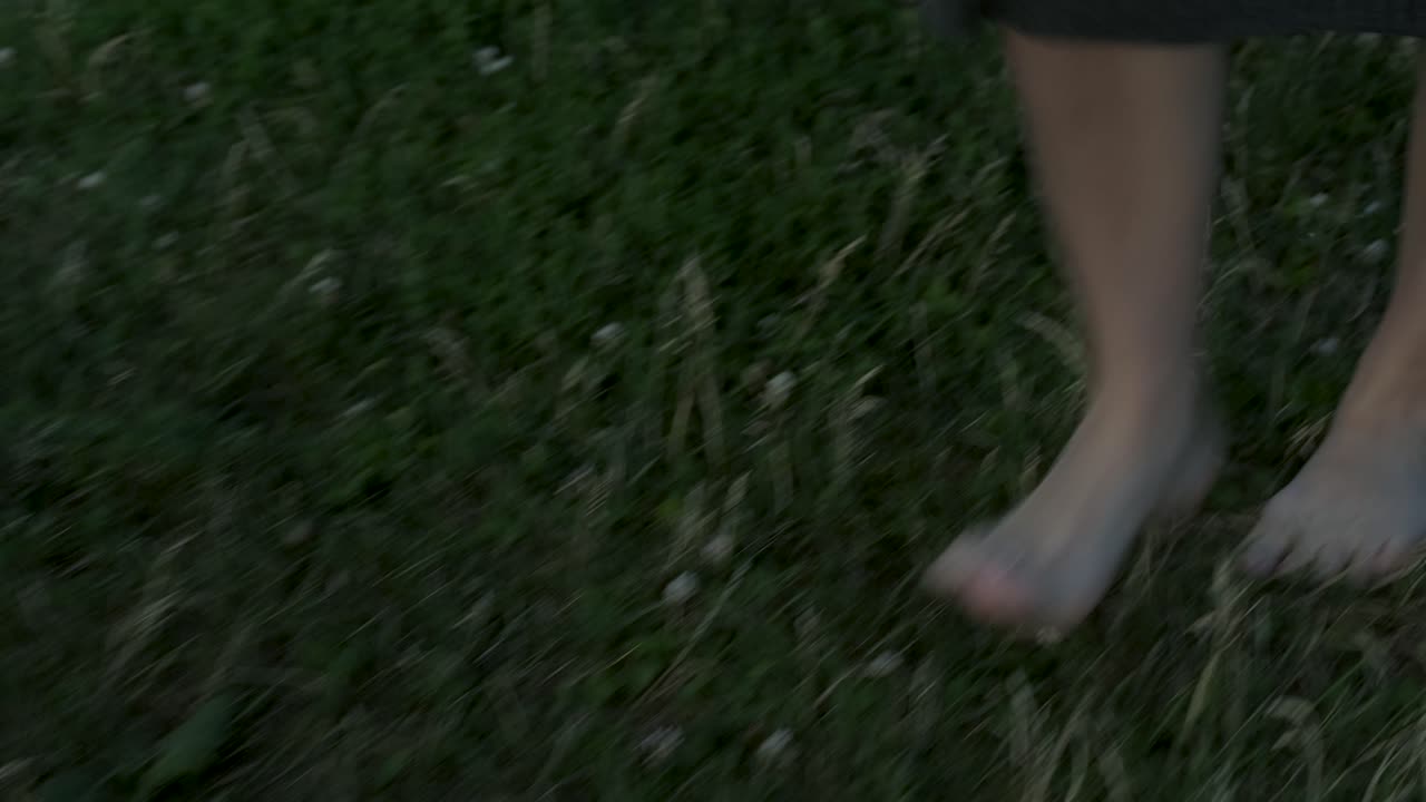 Slow-motion of a woman walking forward and sitting on a blanket in a park in Montreal