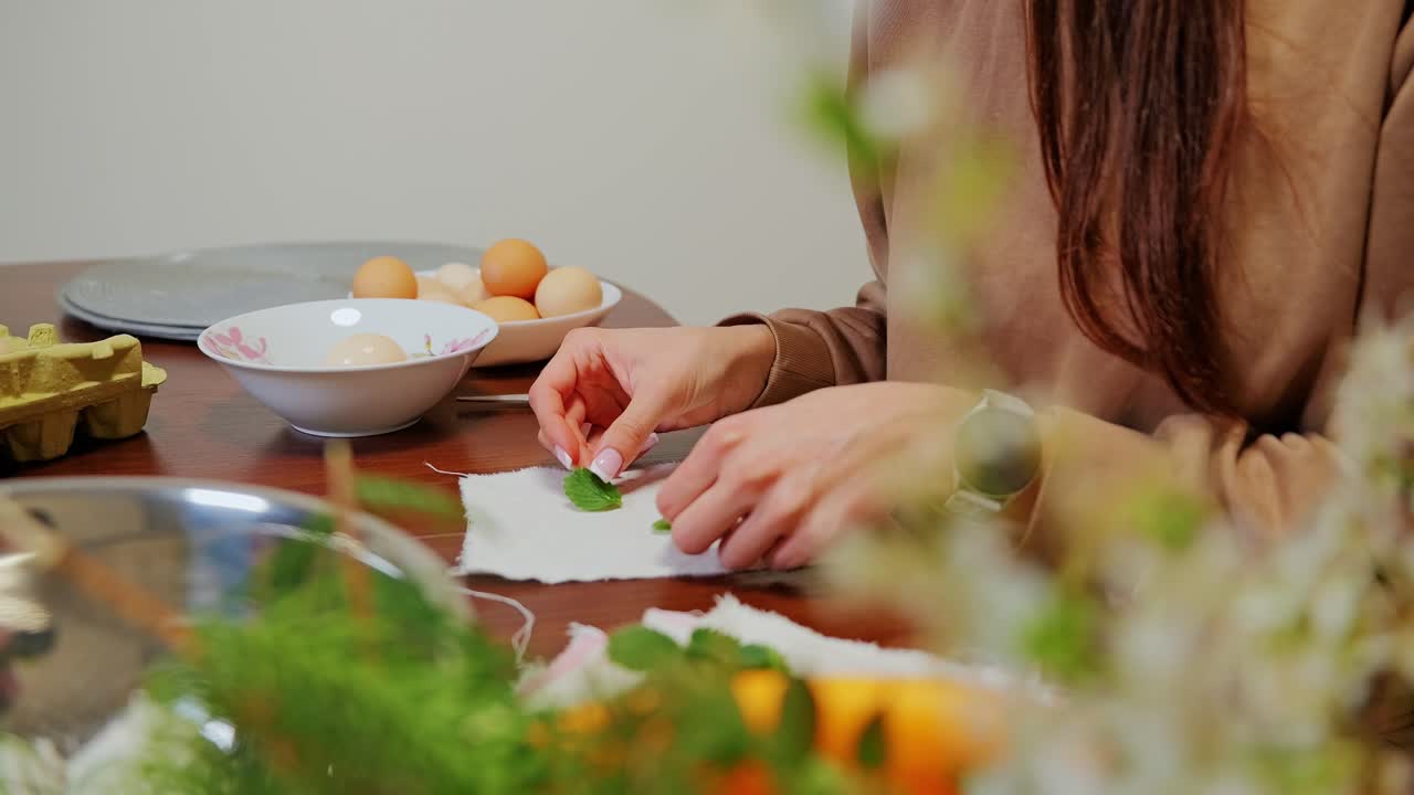 Hands placing leaves on eggs before wrapping in gauze for natural Easter dyeing