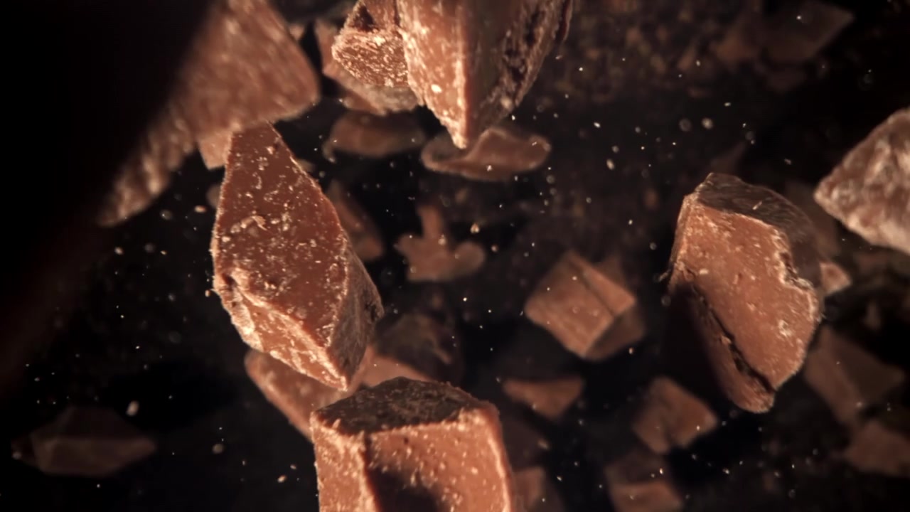 Pedaços Deliciosos de Chocolate Caindo em Câmera Lenta Contra um Fundo Escuro