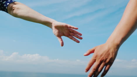 young couple holds hands against a blue sky