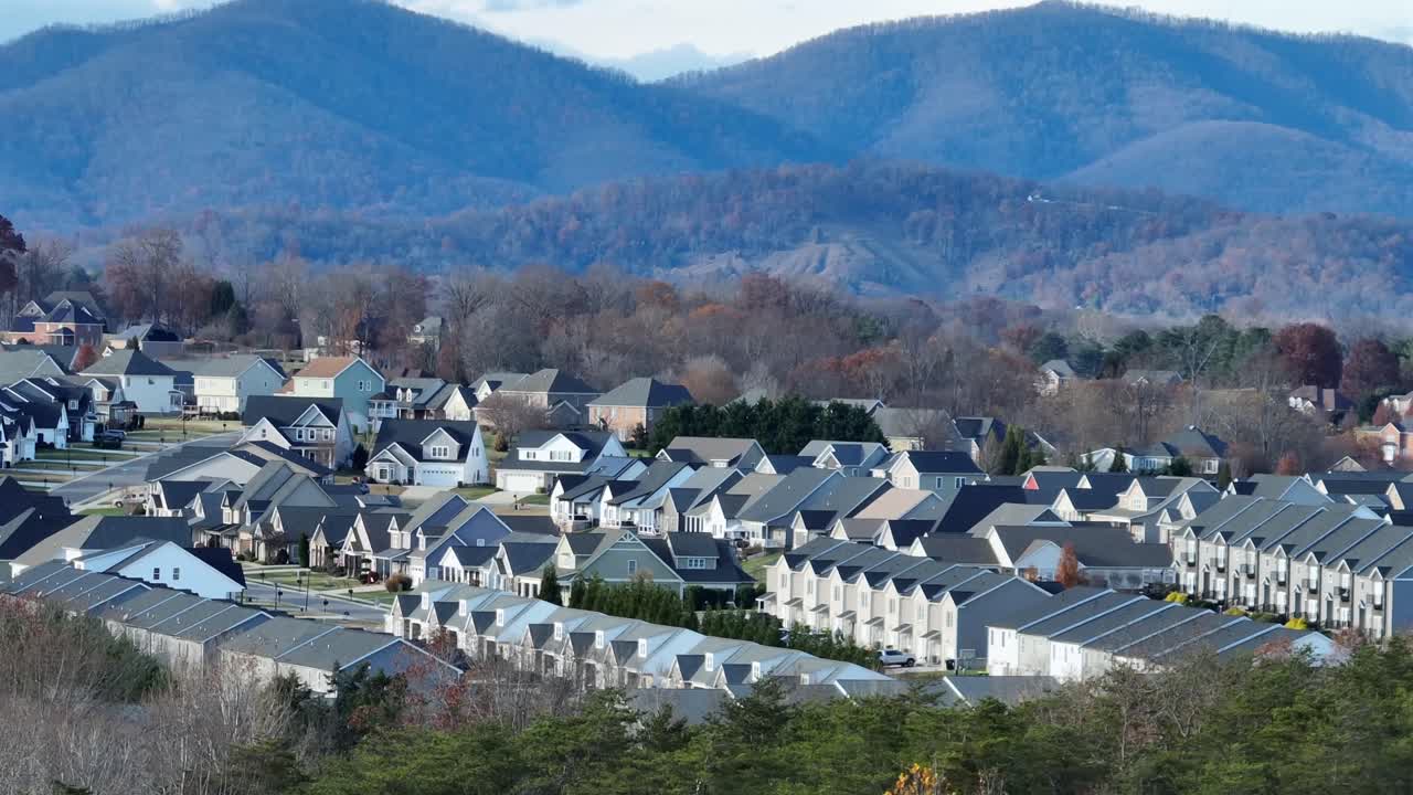バージニア州郊外の近代的な住宅地。背景には、統一された一戸建て住宅、静かな通り、なだらかな丘が広がり、現代的なアメリカの住宅開発を示しています。空撮のワイドショット。