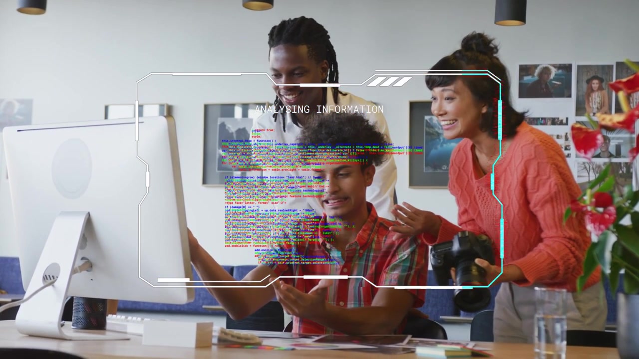 Seated man clicking mouse and launching HUD overlay across monitor while team reviewing design