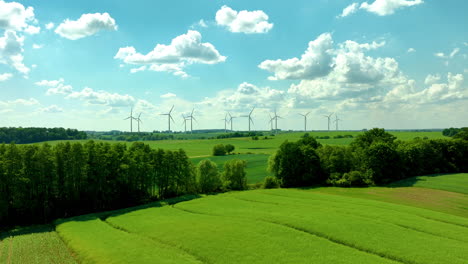 a vast green field with wind turbines under a bright blue sky with scattered clouds