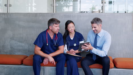 three doctors checking information on a tablet in hospital