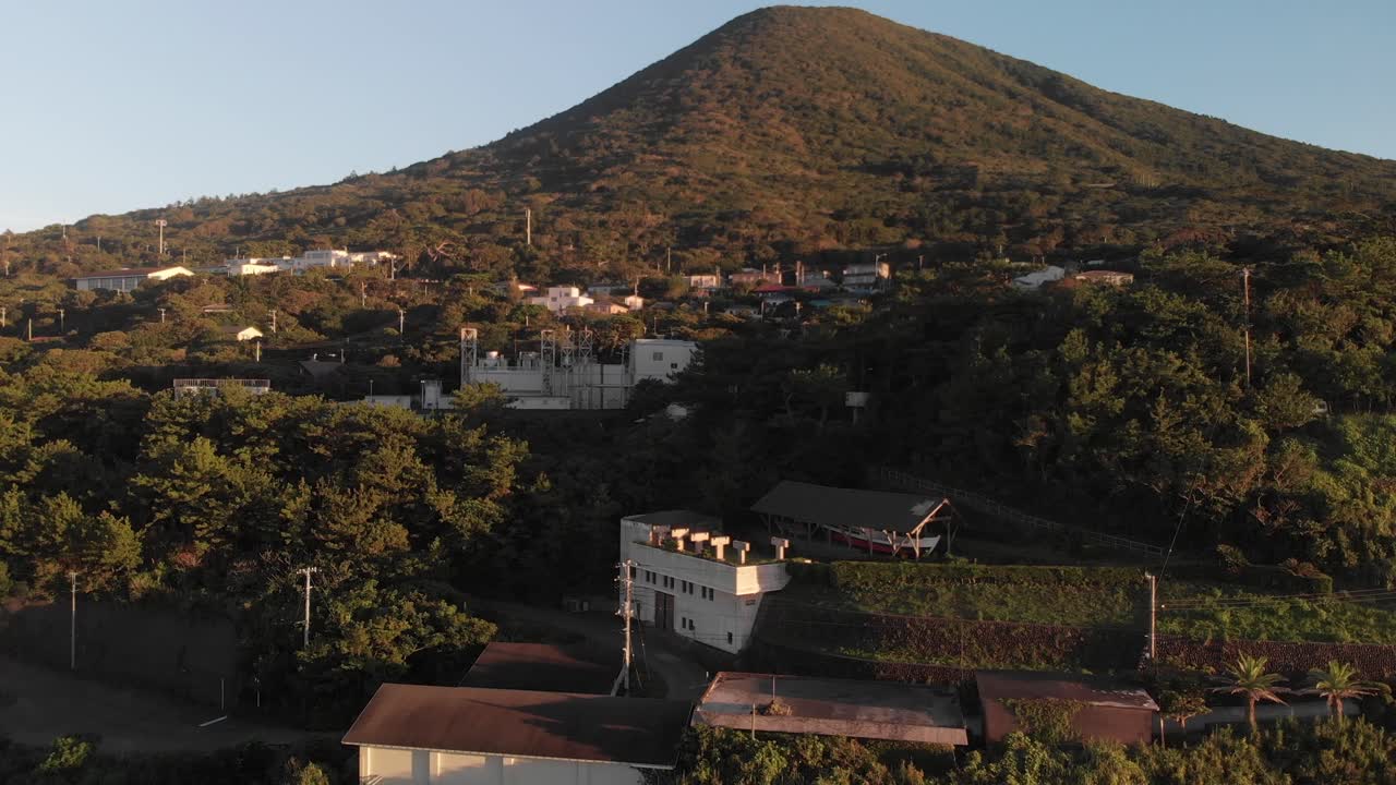un dron aéreo en ascenso disparó sobre una montaña alta con vegetación densa y un pequeño pueblo