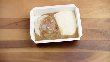 frozen food in a meal packed container melting at room temperature on a dining table