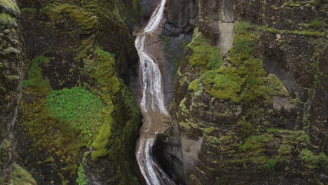 super smooth tilt down view of waterfalls running into the canyons of fjadrargliufur in iceland's dramatic wilderness landscape
