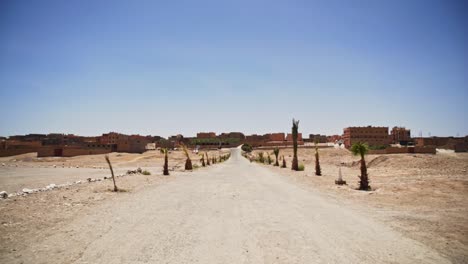 dry road leading to small village with buildings in sahara desert, static shot