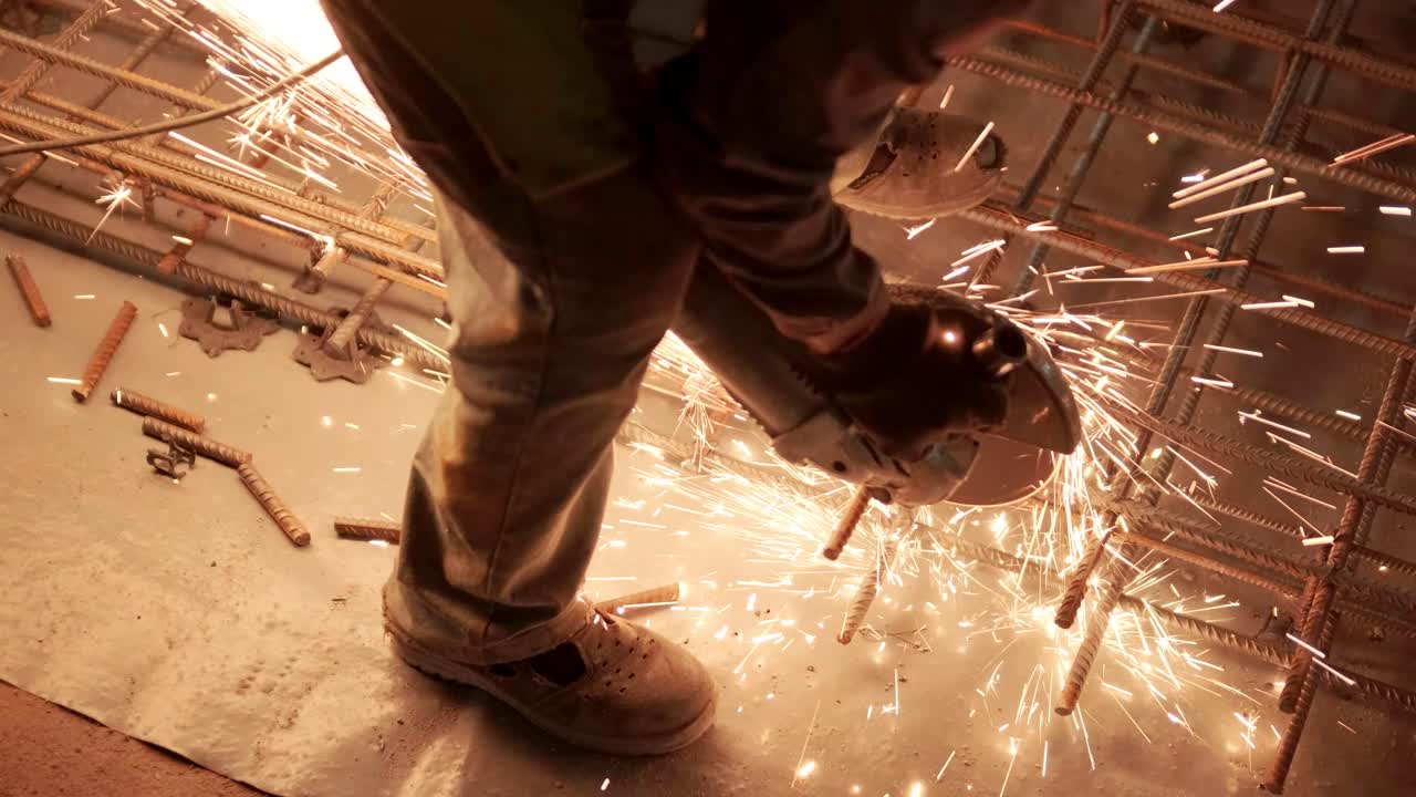 Industrial professional worker is cutting metal rebar with a circular saw. Construction of a factory, hangar