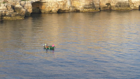 pescadores en un pequeño bote flotando en el mar adriático en polignano a mare, apulia, italia