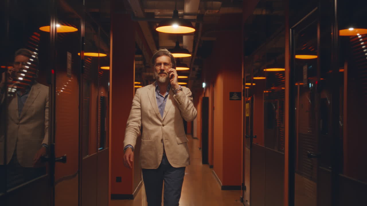 Happy Black Businessman in a Suit Talking on a Phone in the Office an Africanamerican Man in a Blazer Smiles while Talking on a Cell Phone in a Welllit Office Environment