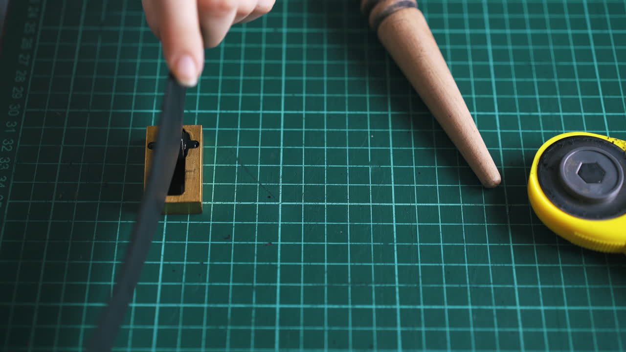 Professional tailor colours leather strip and demonstrates